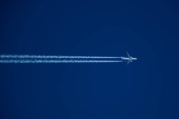 istock Airplane in the blue sky with white contrail 2205766680