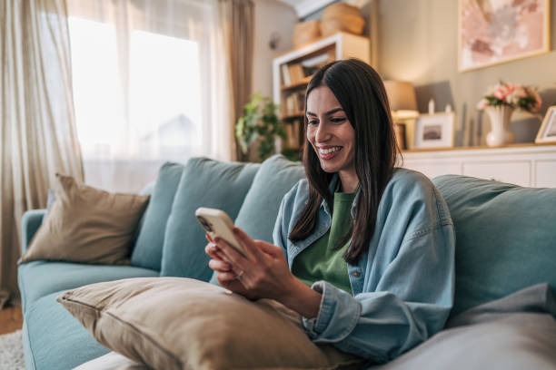 istock Young woman relaxing on sofa using smartphone at home 2205767152