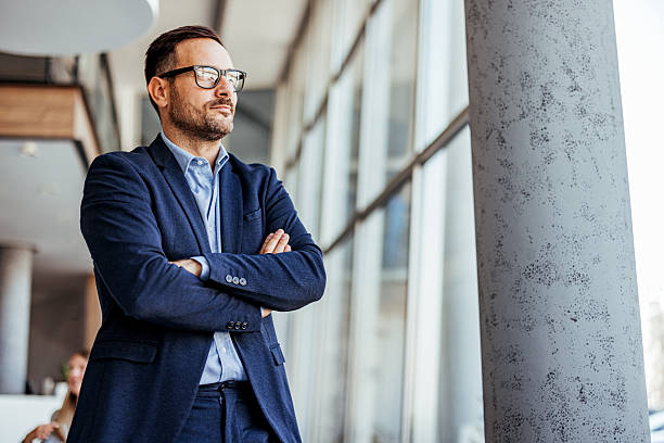Confident Businessman Standing Near Large Modern Office Windows