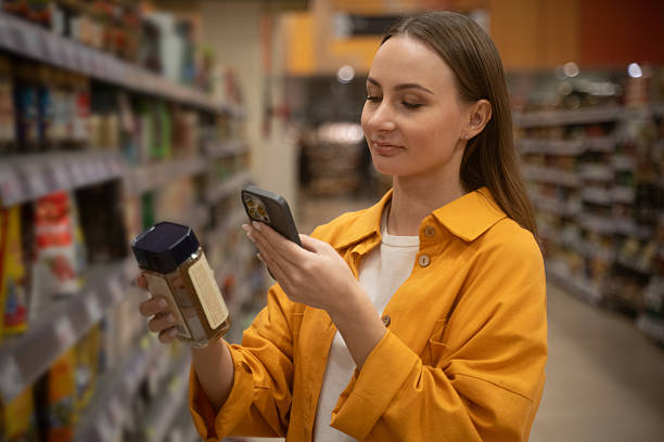 Woman scans can of coffee in store aisle while shopping for groceries and checking prices stock photo