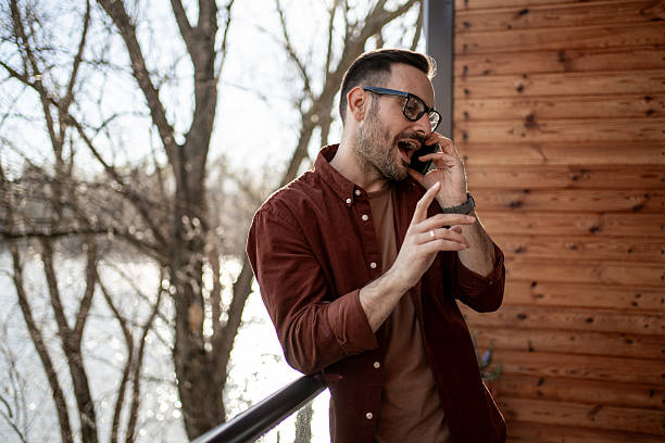 istock Young man talking on the phone on balcony overlooking river 2205769518