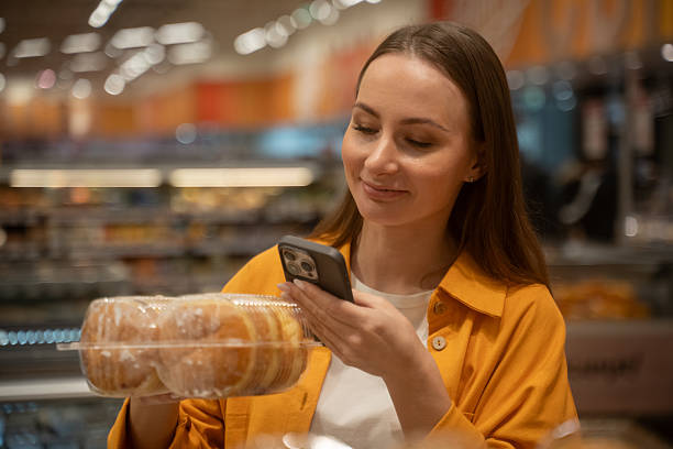 Woman scans donuts in store while shopping for sweet treats during afternoon stock photo