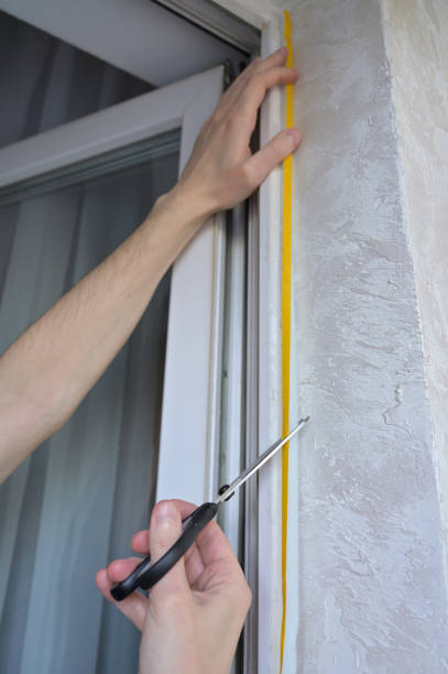 istock A man cuts the foam adhesive tape with scissors. Insulates windows and balcony doors. Budget renovation in the apartment. Preparation for the cold snap. Heating problem in apartment buildings 2205774597