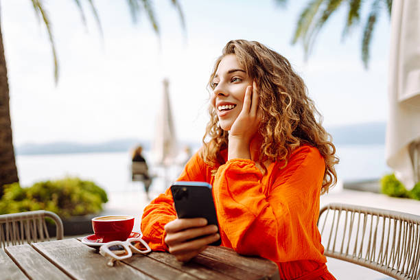 istock Happy woman at summer cafe drinking coffee and using mobile phone. 2205774828