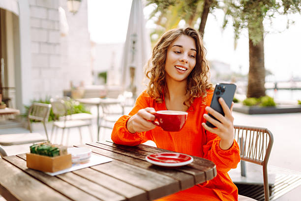 istock Happy woman at summer cafe drinking coffee and using mobile phone. 2205774838