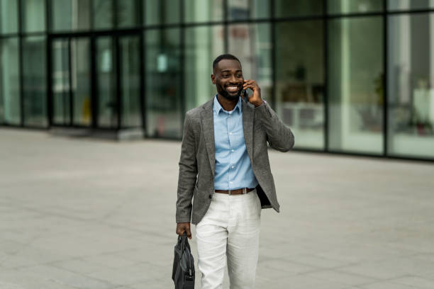 istock Smiling black businessman using phone outdoors. 2205775147