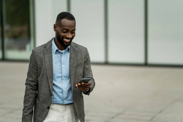 istock Smiling black businessman using phone outdoors. 2205775167