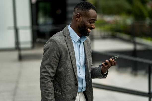 istock Smiling black businessman using phone outdoors. 2205775210