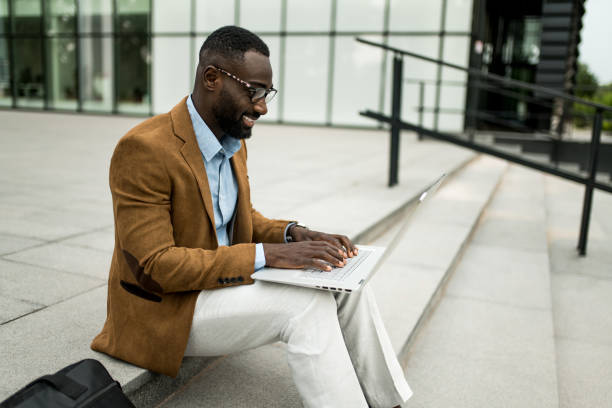 istock Smiling black businessman using laptop outdoors. 2205775643