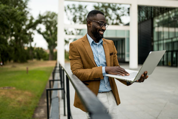 istock Smiling black businessman using laptop outdoors. 2205775704