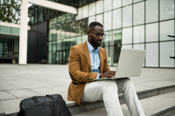 istock Black businessman using laptop outdoors. 2205775731