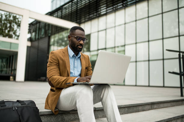 istock Black businessman using laptop outdoors. 2205775755