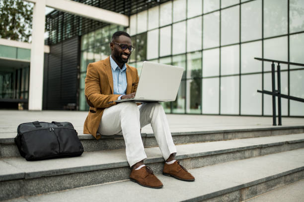 istock Smiling black businessman using laptop outdoors. 2205775788