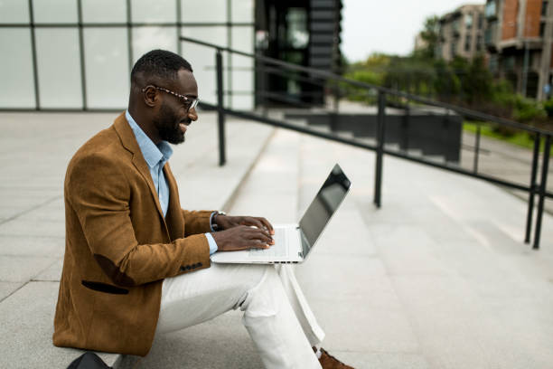 istock Smiling black businessman using laptop outdoors. 2205775819