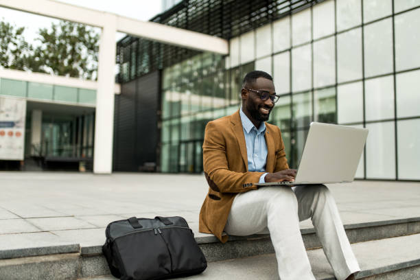 istock Smiling black businessman using laptop outdoors. 2205775861