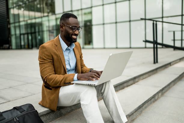 istock Smiling black businessman using laptop outdoors. 2205775967