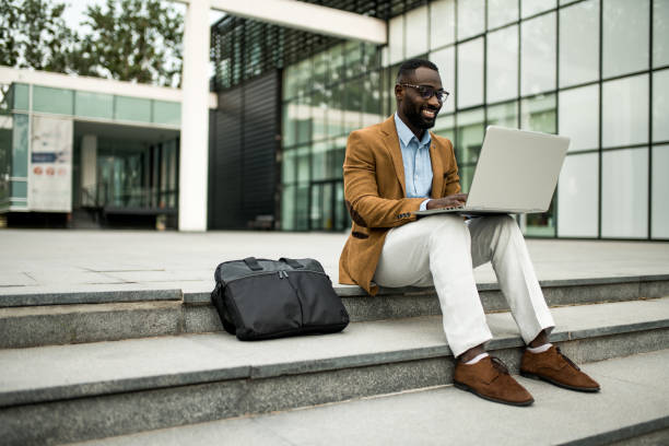 istock Smiling black businessman using laptop outdoors. 2205776007