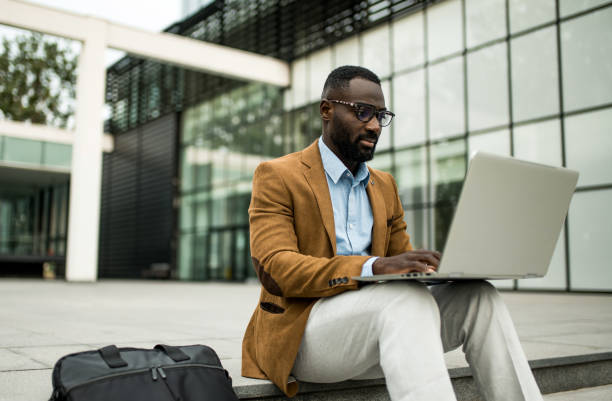 istock Black businessman using laptop outdoors. 2205776155