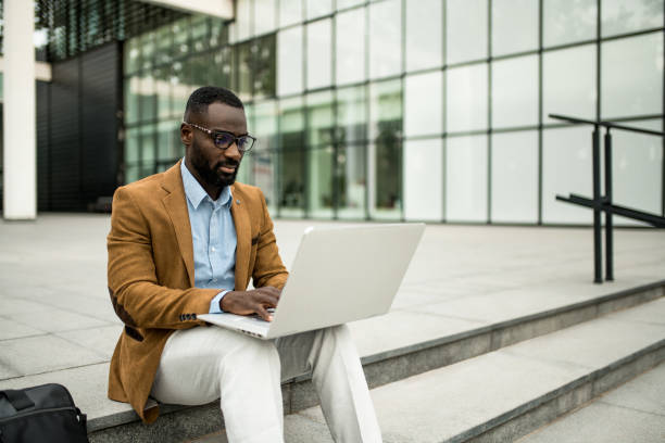 istock Black businessman using laptop outdoors. 2205776173