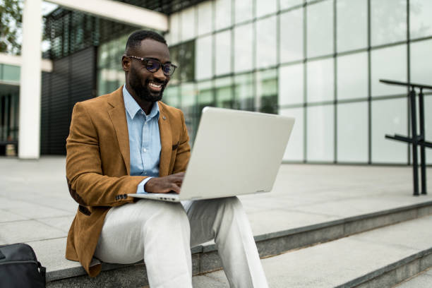 istock Smiling black businessman using laptop outdoors. 2205776194