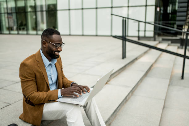 istock Smiling black businessman using laptop outdoors. 2205776209