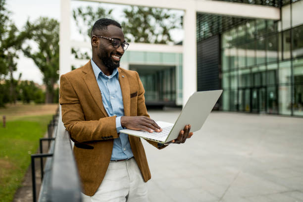 istock Smiling black businessman using laptop outdoors. 2205776258