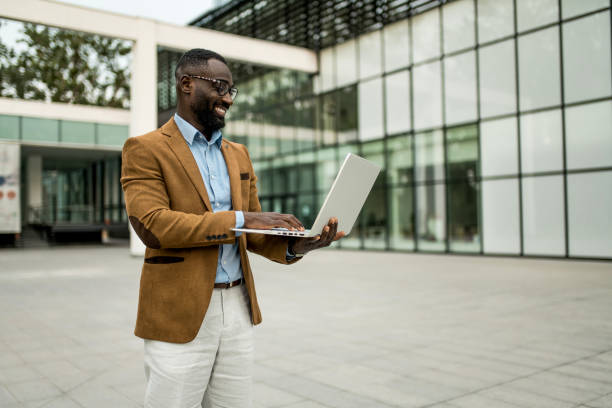 istock Smiling black businessman using laptop outdoors. 2205776275