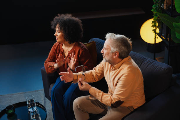 istock Mature Couple Talking and Gesturing While Sitting on Sofa in Living Room 2205776818