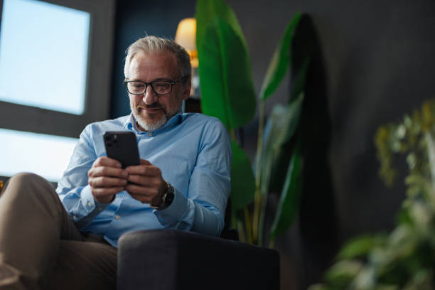 istock Smiling mature businessman using smart phone at home 2205776839