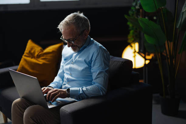 istock Focused mature businessman working on laptop in cozy home office 2205776842