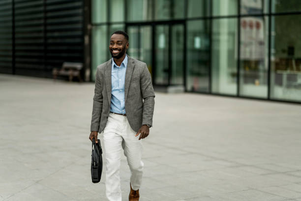 istock Smiling black businessman walking from work outdoors. 2205776940