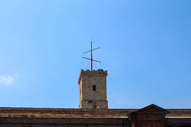 Barcelona, Spain 21. July 2024, Montjuic Castle tower with mast and flags standing tall against a vibrant blue sky in Barcelona, Spain