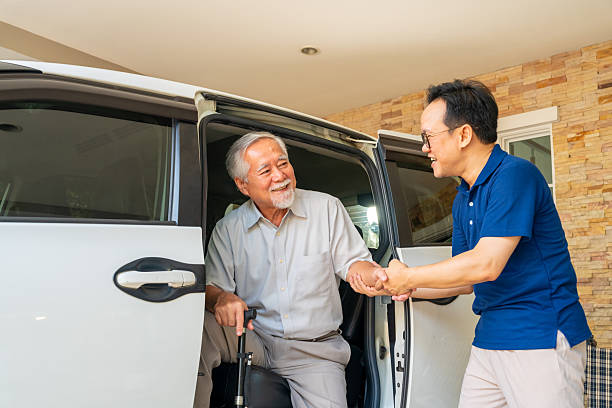 Caregiver helping senior man get in the car.