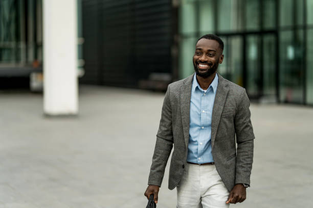 istock Smiling black businessman walking from work outdoors. 2205778127