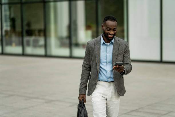 istock Smiling black businessman using phone outdoors. 2205778149