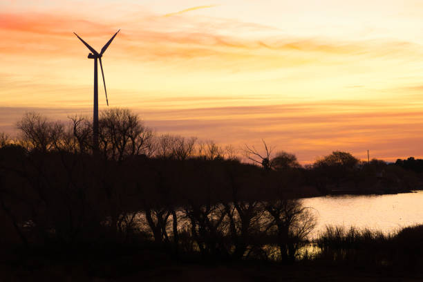 Sunrise in Palmdale, California with mountains and windmill in the background with the sun reflecting on the lake.