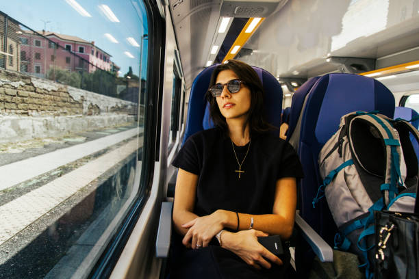 istock Woman Traveling on a Train, Relaxing By the Window With a Backpack 2205783284