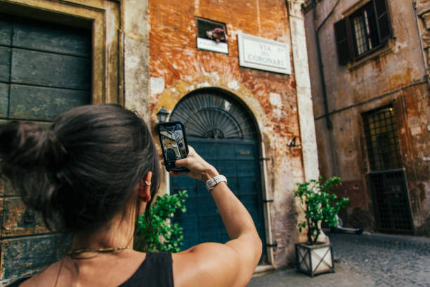 istock Woman Capturing Rustic Architecture with Smartphone on Quaint Street 2205783778