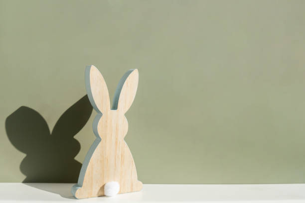 istock Minimalistic creative Easter concept. Two Easter bunnies under symbolic roof on green background. Celebration Easter holiday at home with family. Poster or greeting card 2205786997