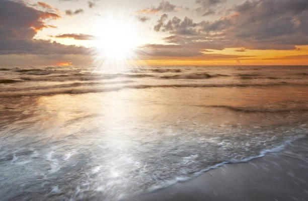 istock Luminous Sunset Over Ocean Waves with Rays Dancing Across the Horizon 2205790620