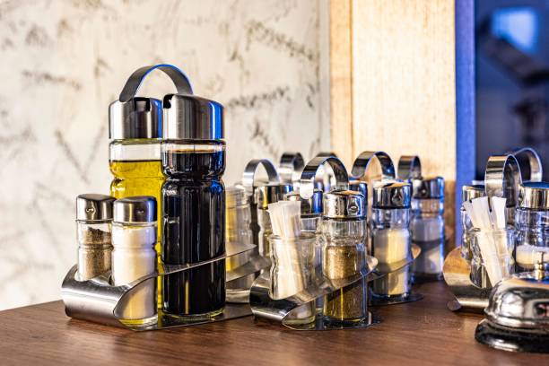 An arrangement of condiment bottles including oil, vinegar, and spices on a polished table surface. Perfect for lifestyle, dining, and food-related themes, showcasing contemporary elegance and practical organization.