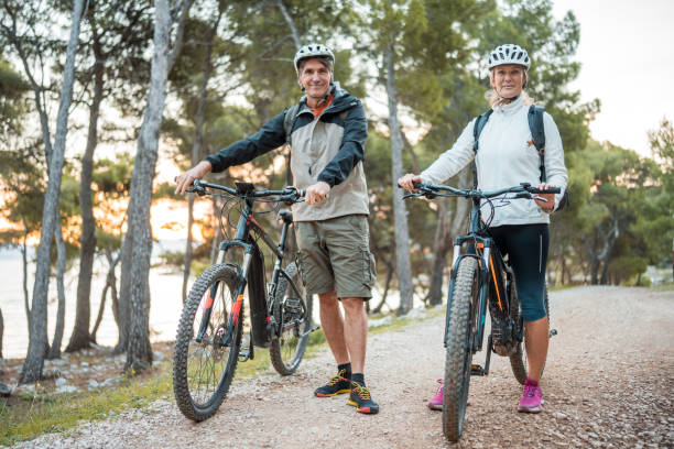 istock Active Senior Couple with Mountain Bikes at Seaside Sunrise 2205791912