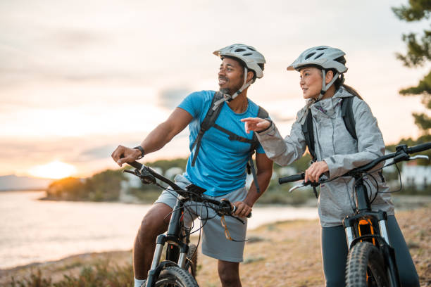 istock Active Asian Woman and Black Man with E-Bikes Enjoying Coastal Dawn 2205791926