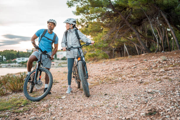 istock Active Diverse Couple with Electric Bikes by the Sea at Dawn 2205791984
