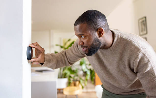Man at home adjusting the temperature on the thermostat