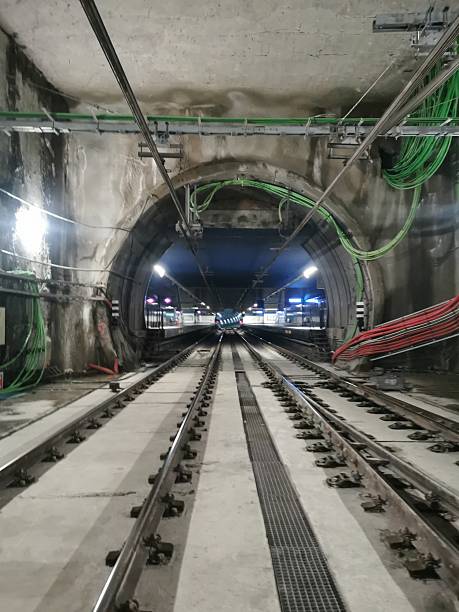 istock Illuminated metro tunnel leading to a station platform. Visible tracks, catenary, cables, and infrastructure. No trains present. Industrial setting with a perspective view of underground transportation 2205804750