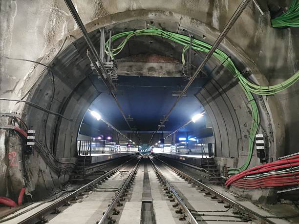 istock Illuminated metro tunnel leading to a station platform. Visible tracks, catenary, cables, and infrastructure. No trains present. Industrial setting with a perspective view of underground transportation 2205804757