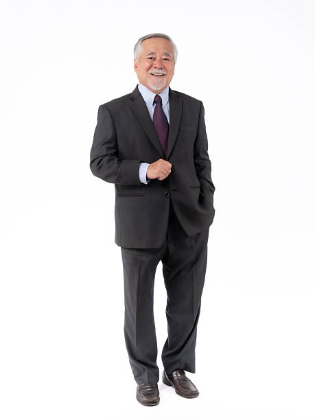 Confident senior businessman in a formal dark suit, standing professional pose with one hand on his jacket and the other in his pocket, isolated on white background, symbolizing leadership, success