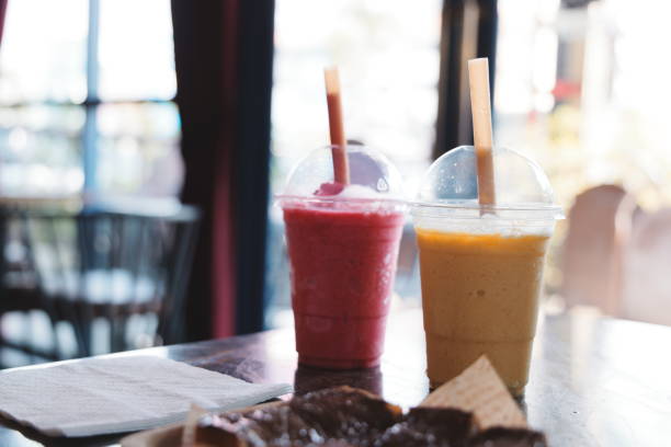Two vibrant smoothies, one pink and one yellow, sit on a table, ideal for a refreshing summer treat