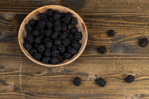 ripe blackberries in a wooden bowl, sour but ripe blackberries on the table, closeup, top view